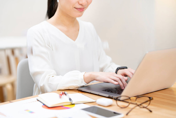Ασιάτισσα νεαρή γυναίκα που δουλεύει με φορητό υπολογιστή - Φωτογραφία, εικόνα