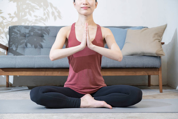 Mujer joven con ropa de yoga haciendo yoga en la habitación - Foto, imagen