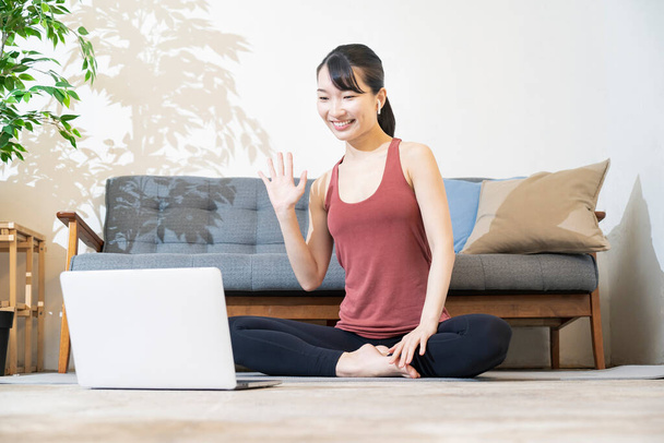 Инструктор по йоге разговаривает с экраном компьютера в комнате - Фото, изображение