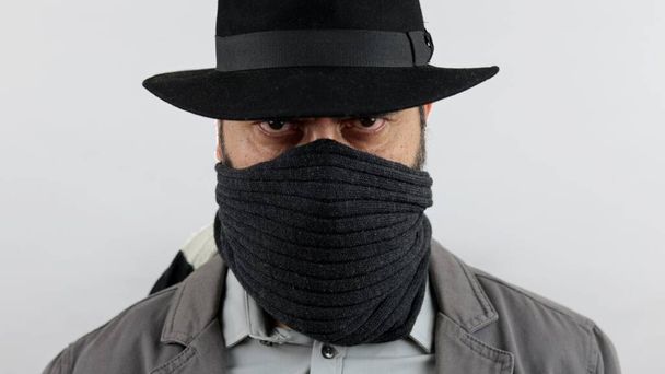 Bandido de Outlow con sombrero y cara cubierta mira a la cámara. - Foto, imagen