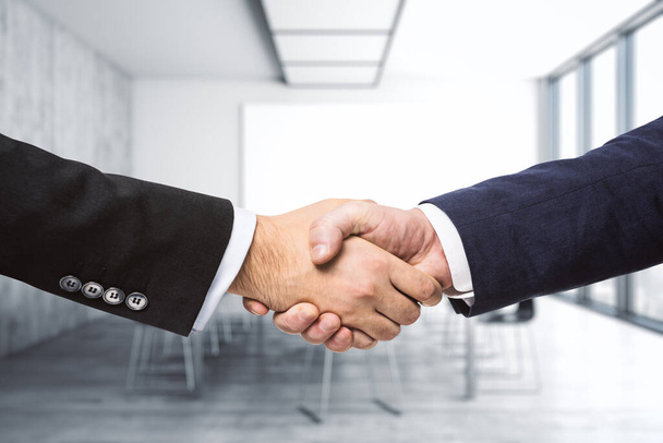 Handshake of two businessmen on the background of bright conference room, partnership concept, close up - Zdjęcie, obraz