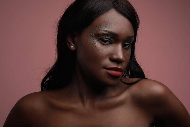 Portrait of young black woman posing in the studio, with glittery make-up. - Photo, image