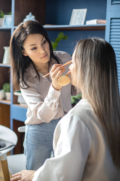Professional female makeup artist applying cosmetics on model face use brush working at beauty salon - Foto, immagini