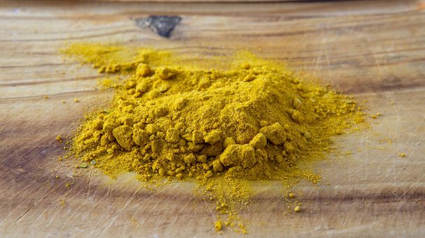 Close view of a bunch of curry powder on top of a wooden surface - Photo, Image