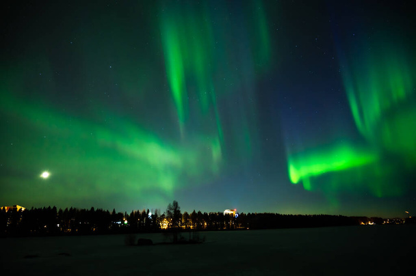 Multibarevná severní světla na noční obloze nad městem. Aurora Borealis nad Švédskými jezerními ostrovy. Severní Švédsko. Zimní hvězdná obloha. - Fotografie, Obrázek