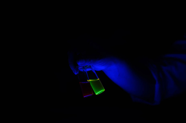 Um cientista químico segurando um par de solução composta fluorescente em frasco para injetáveis de vidro pequeno para pesquisa biotecnológica - Foto, Imagem