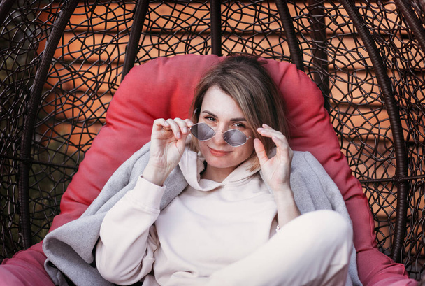 Young happy girl in sunglasses enjoys a rest in nature in a chair - Photo, image
