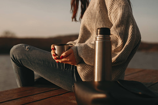 Woman with hot coffee resting near lake - Photo, Image