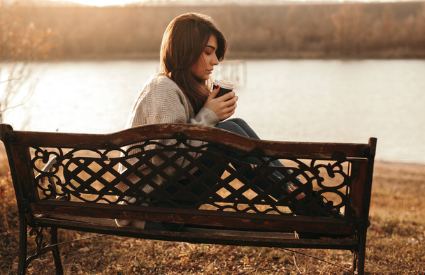 Serene woman with cup of takeaway coffee near lake - Foto, Imagem