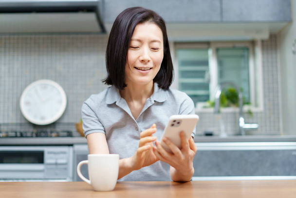 Mulher asiática operando um smartphone no quarto - Foto, Imagem
