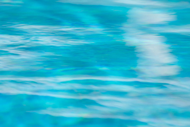 Background of waves, reflections, refractions and abstract diffractions, in the blue, clean and crystalline water of a swimming pool in the municipality of Gallur, Aragon, Spain, on a summer day. - Photo, Image