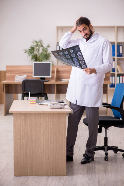 Молодой врач-рентгенолог сидит в кабинете - Фото, изображение