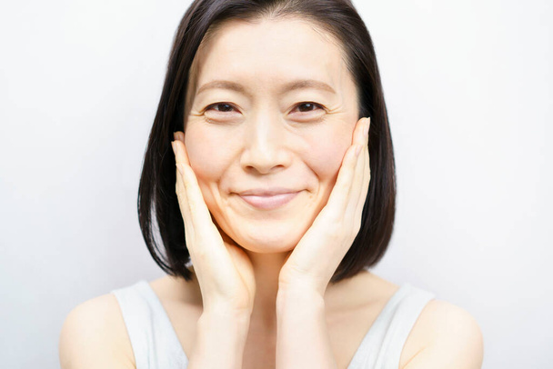 Donne asiatiche che si toccano il viso (anni 40 o 50))  - Foto, immagini