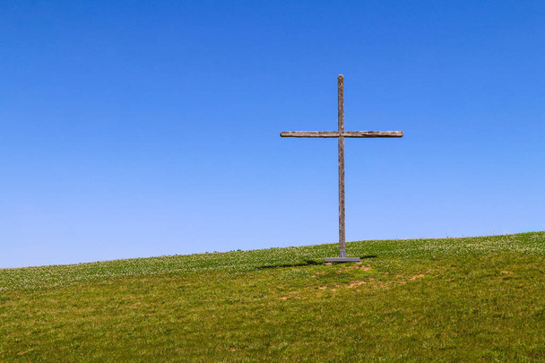 large wooden christian symbol cross standing on a grass hill or rural grassy hillside as a nature landscape religious background - Zdjęcie, obraz
