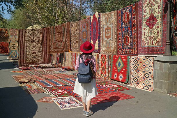 Reisende beeindruckt von den atemberaubenden Teppichen auf dem Vernissage-Markt in der Innenstadt von Jerewan, Armenien - Foto, Bild