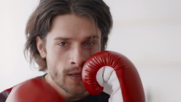 Boxerský výcvik. Detailní záběr mladého aktivního muže v boxerských rukavicích punching na kameru, cvičení v sebeobraně - Záběry, video