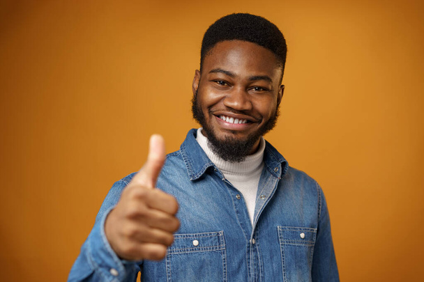 Happy smiling african american man showing thumb up, yellow background - Foto, afbeelding