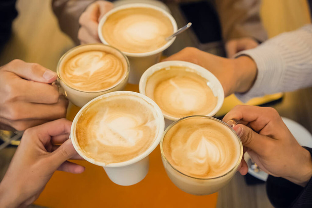 Groupe de personnes tenant des tasses dans leurs mains acclamant avec des boissons chaudes comme le café et le cappuccino - Photo, image