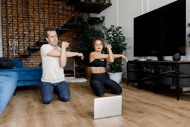 young couple training  at home with  laptop on the floor - Φωτογραφία, εικόνα
