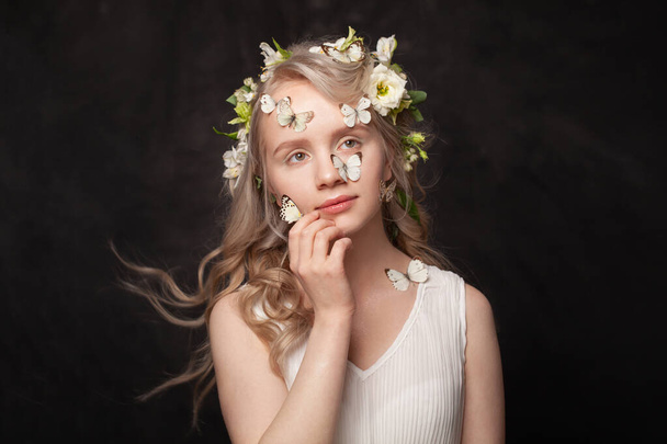 Happy young woman with white spring flowers and butterfly dreaming on black background - Foto, immagini