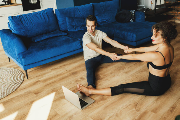 young couple training  at home with  laptop on the floor - Zdjęcie, obraz