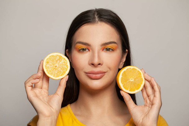 Fiatal szép egészséges modell tiszta bőr és egyenes haj gazdaság citrom gyümölcsök fehér háttér portré. Táplálkozás, bőrápolás és arckezelés - Fotó, kép