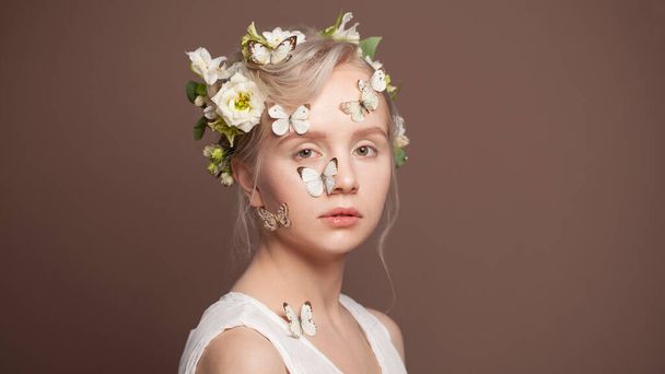 Dolce giovane donna con fiori bianchi primaverili e farfalla su sfondo marrone - Foto, immagini