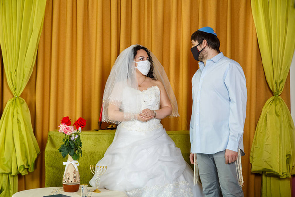 During the chupa ceremony in the synagogue, the masked Jewish bride and groom stand side by side. Horizontal photo - Photo, Image
