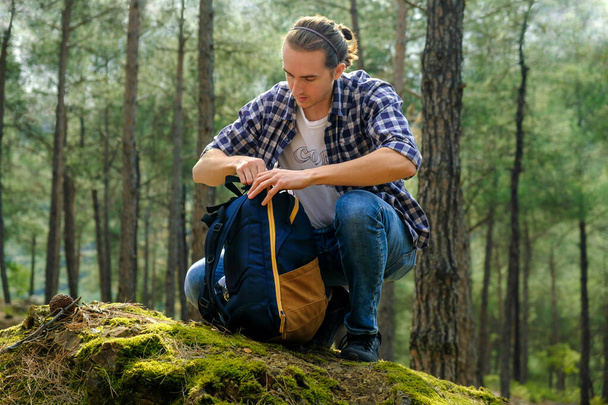 Fiatal aktív férfi hátizsákkal az erdőben napsütésben. Helyi utazási koncepció - Fotó, kép