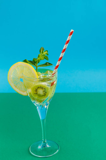 Kiwi cocktail garnished with lemon and mint in a glass on a napkin on a green background. Vertical photo - Foto, imagen