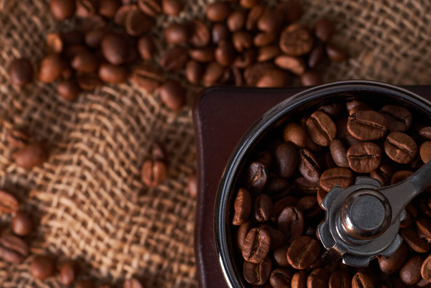 Kávébab és daráló az asztalon rusztikus háttérrel - Fotó, kép
