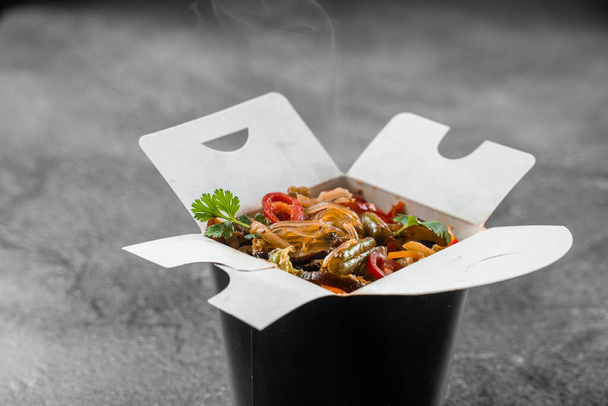 Wok in scatola tagliatelle di riso in contenitore di cibo nero. Servizio di consegna fast food. Cibo cinese da asporto - Foto, immagini