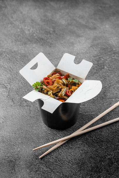 Wok in box rice noodles in black food container. Fast food delivery service. Takeaway chinese street meal - Фото, зображення