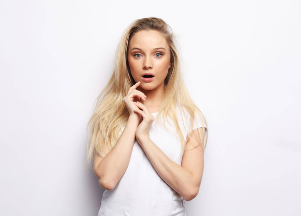 Shot of stupefied shocked blonde woman keeps mouth widely opened, looks at camera over white background - Фото, изображение