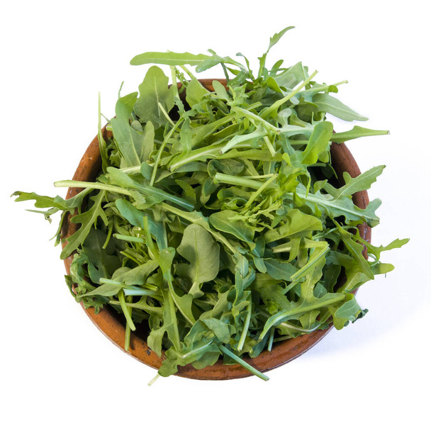 Bright fresh juicy arugula leaves on brown clay plate isolated on white background top view - Foto, Bild