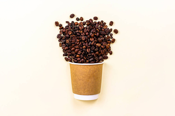 Taza desechable de cartón marrón con café y granos de café tostados con espacio para copiar sobre fondo claro. Concepto de comida para llevar. - Foto, imagen