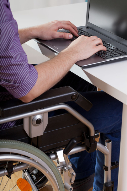 Uomo sulla sedia a rotelle che lavora sul computer portatile
 - Foto, immagini