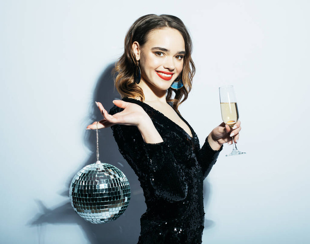 lifestyle, party and people concept: Young happy woman wearing black dress, holding disco balls - Foto, Bild