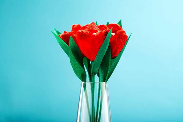 Red tulips made of paper and marshmallows inside the bud on a blue background with place for text. - Foto, imagen