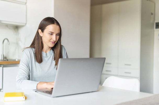 Charming young woman using laptop computer for working from home, - Foto, Bild