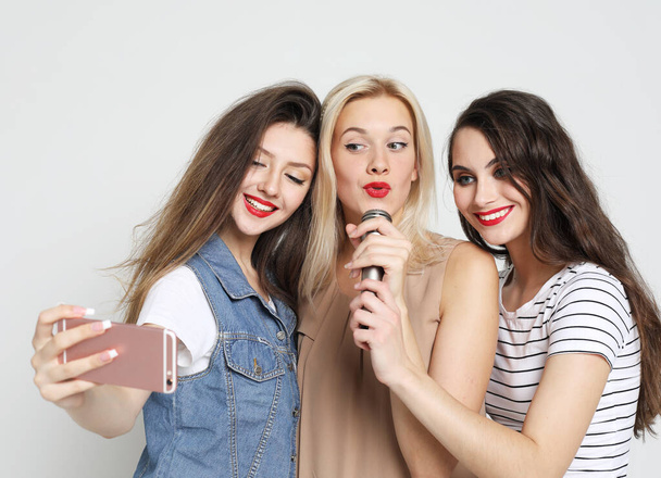 lifestyle, emotion and people concept: three beauty girls with a microphone take selfie with smartphone - Fotografie, Obrázek