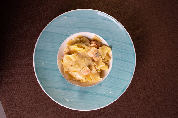pasta with salmon and cheese on a blue plate top view. - 写真・画像