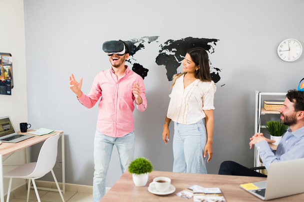 I can't believe this VR tour. Happy handsome man using virtual reality glasses and feeling excited while looking at pictures of a trip abroad at the travel agency - Fotoğraf, Görsel