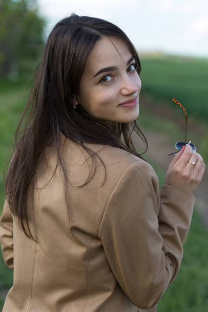 Portret pozytywnej wesołej brunetki w zielonym wiosennym parku. - Zdjęcie, obraz