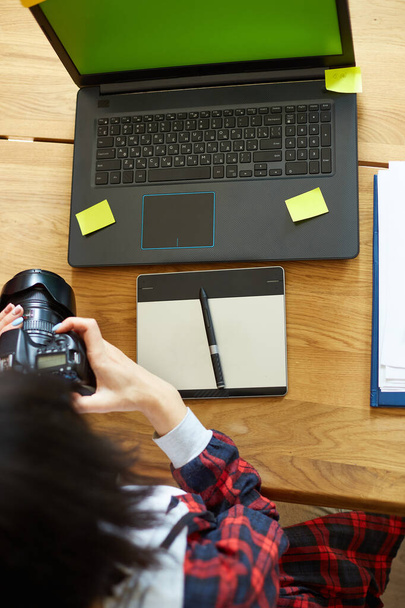 Фотограф-женщина, работающая в креативном офисе с камерой, за столом и ретуширующей фотографией на ноутбуке, ретуширующее рабочее место в фотостудии, успешный внештатный творческий бизнес, Photography Concept - Фото, изображение