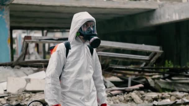 Fertőtlenítő brigád munkás áll között épület romjai - Felvétel, videó