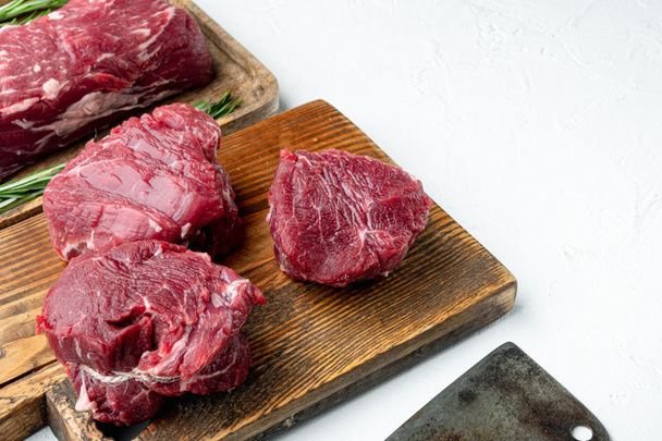 A raw fresh marbled beef steak set, on wooden cutting board, on white stone  surface, Filet mignon cut, with copy space for text - Foto, imagen