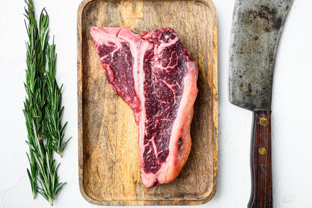 Dry aged Raw T bone or porterhouse marbled beef meat Steak with herbs and spices set, on white stone  background, top view flat lay - Zdjęcie, obraz