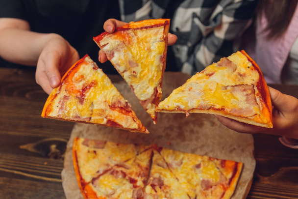 Close up female hand holding, taking slice, piece of pizza friends sitting together in cafe, spending free . - Foto, imagen