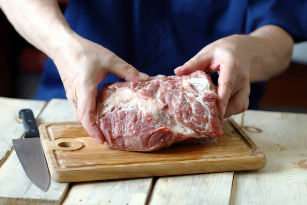 Carne crua nas mãos do chef em uma tábua de madeira. Cozinhar carne. - Foto, Imagem